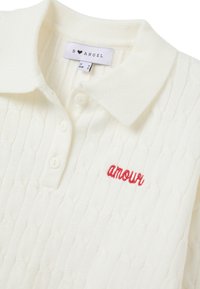 Polo in maglia cable-knit color crema, con patta a tre bottoni e ricamo rosso "amour". Tessuto morbido con design del colletto classico.