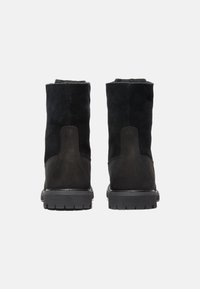 Botas de cuero vuelta negras hasta el tobillo con un acabado texturizado, que cuentan con una suela de goma y un talón reforzado, adecuadas para diversas condiciones al aire libre.