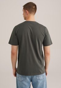 Mörkgrå bomulls-t-shirt med rund halsringning och korta ärmar, med en smooth yta och avslappnad passform, bärs med ljusblå jeans.