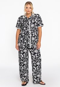 Schwarz-weißes Blumenmuster-Set mit einer kurzärmligen Knopfleiste und weit geschnittenen Hosen, ausgestattet mit dekorativen Verzierungen an den Ärmeln.