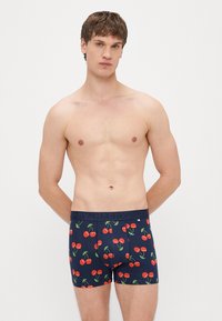 Tumši zili bokseršorti ar ķiršu rakstu, ar vienkrāsainu jostiņu, uz kura iespiests vārds "HAPPY". Izgatavoti no mīksta, elastīga auduma.