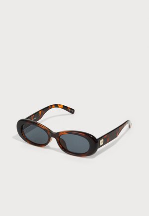 Gafas de sol de carey marrón con lentes ovalados. Lentes gris oscuro con un marco de plástico liso y acentos de logo en las patillas.