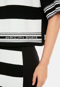 Black and white striped top made of ribbed fabric. Features a logo label and textured stripes; has short, wide sleeves and relaxed fit.