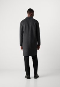 Grijze lange jas met een rechte snit, gemaakt van textiel met een structuur, met een minimalistisch ontwerp en subtiele stiksel-details op de achterkant.