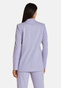 Licht lavendelkleurige op maat gemaakte blazer met een gestructureerd ontwerp, scherpe revers en lange mouwen. Glad stoffen met zichtbare naden en een minimalistische stijl.