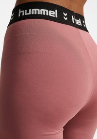 Roze legging met een soepele textuur en een zwarte tailleband met witte "hummel" branding en een chevronpatroon.