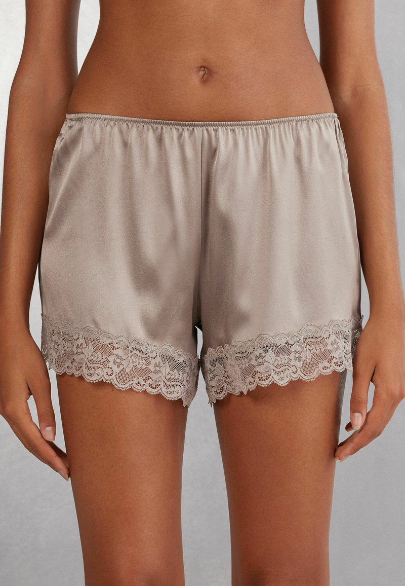 Sidenlika taupe-shorts med elastisk midja och delikat spetsdetalj vid fållen, som erbjuder en mjuk textur och en bekväm passform.