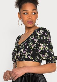 Top curto preto com padrão floral, apresentando mangas bufantes, um decote quadrado e um detalhe de laço ao centro, adornado com padrões de borboletas coloridas e flores.