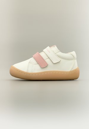 Zapato sintético blanco con tiras de velcro rosa claro y suela de goma color canela. Presenta detalles cosidos y un diseño de punta redondeada.