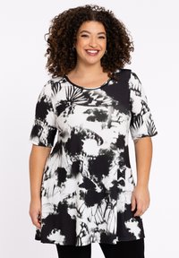 Zwart-witte tuniek met korte mouwen, ronde halslijn en abstracte bloempatronen. Zachte, rekbare stof met een relaxte pasvorm.