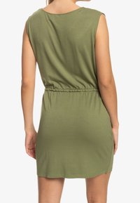 Zelené lehké šaty s kulatým výstřihem, krátkými rukávy a elastickým pasem. Design obsahuje střih ke kolenům a hladký textura.