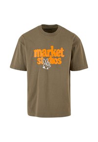 Olivenfarget bomulls t-skjorte med stor oransje og hvit grafikktekst "market studios" med et fredstegndesign under.