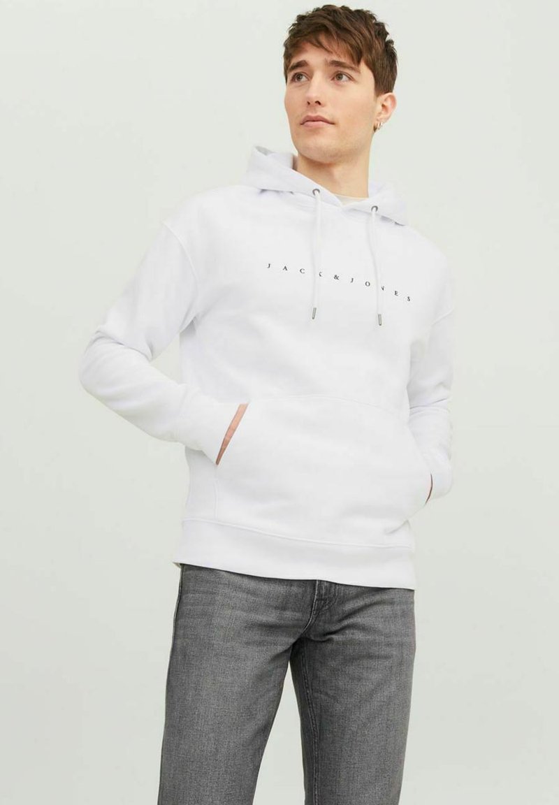 Haut à capuche blanc avec cordon de serrage, poche avant et logo imprimé au-dessus de la poche. Assorti à un jean gris. Texture lisse, design décontracté.