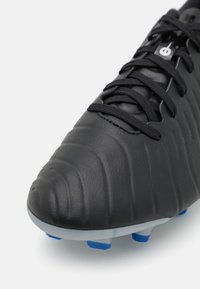 Crampons de football noirs avec une tige en cuir texturé, des lacets noirs et une semelle grise. Des pointes bleues assurent une traction sur le terrain.