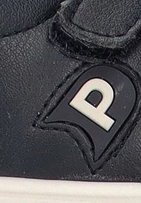 Zapatilla negra con parte superior de cuero texturizado que presenta un logo "P" blanco en un parche negro redondeado cerca del área de los cordones. Suela de goma blanca.