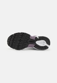 Talpă din cauciuc negru cu model texturat de protecție, prezentând accente de violet deschis și alb pe partea superioară a sneakerilor. Design curbat cu suport pentru arc.