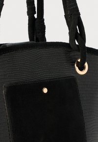 Borsa nera in ecopelle testurizzata, con dettagli in suede liscio, elementi in oro e doppi manici morbidi per il trasporto.