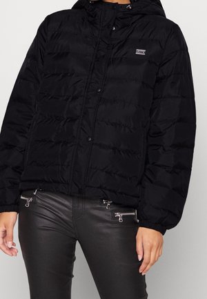 Veste en duvet noire avec capuche, présentant des sections matelassées horizontales et un petit patch logo. Texture lisse et fermetures à pressions.