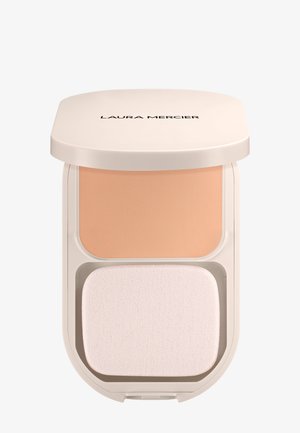 Polvo compacto que presenta un polvo mate de un beige claro y una suave esponja aplicadora blanca, alojado en un estuche redondeado de color crema.