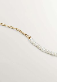 Collar de cadena de oro con perlas blancas irregulares, superficie texturizada y un cierre distintivo. Diseño elegante con materiales en contraste.