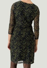 Czarna sukienka z długimi przezroczystymi rękawami, ozdobiona zielonym kwiatowym wzorem. Miękka, lekka tkanina, dopasowany krój o długości midi.