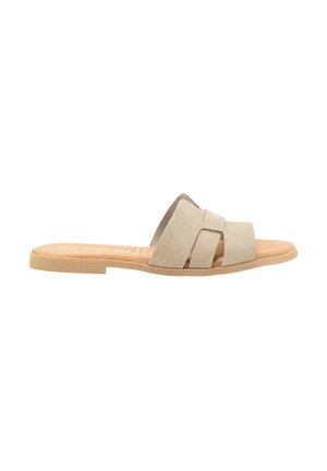 Zapatos de slide de ante beige con dos correas cruzadas, suela plana de goma natural y plantilla contorneada para mayor comodidad.