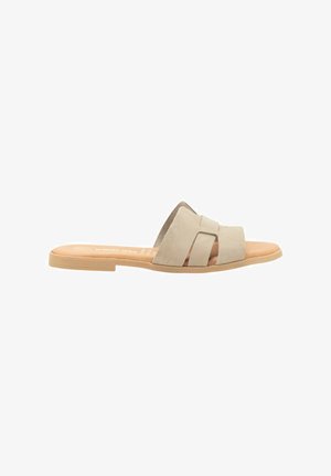 Zapatos de slide de ante beige con dos correas cruzadas, suela plana de goma natural y plantilla contorneada para mayor comodidad.