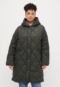 Zelena kaputka s kapuljačom, od tamnozelene tkanine, podstavljena i sa dijamantnim uzorkom, s prednjim kopčanjem na dugmad, bočnim džepovima i širokim krojem. Mekana, sjajna tekstura.