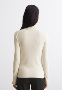 Gestreifter Rollkragenpullover in Cremefarbe, mit langen Ärmeln und figurbetontem Schnitt, aus einem weichen, elastischen Strickstoff gefertigt.