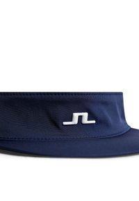 Marinblå skärm med en slät tygkvalitet, en bred skärm och en vit logotyp på frambandet. Har rena sömmar och en enkel design.