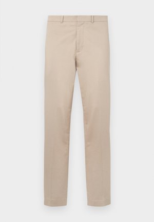 Beežid sirge lõikega püksid, millel on vööaasad, ees lukk ja nööpkinnitus, asetatud valgele taustale.