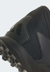 Zapato deportivo negro con una parte superior texturizada, acentos suaves y una suela resistente con tacos de tracción multidireccional.