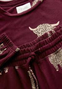 Burgundia värvi kodutekstiilide komplekt, millel on nööriga vöökoht; sisaldab beeži loomamustrit ja pehmet kangast. Sildil on tekst "Pühenda aega unistamiseks".