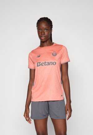 Oransje fotbalstrømpe med geometrisk mønster, grå detaljer og "Betano"-logo. Kombinert med grå shorts. Atletisk, lett stoffdesign.