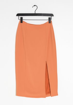 Jupe crayon pêche-orange avec une fente latérale, réalisée en tissu lisse, présentant des lignes épurées et des coutures minimales. Suspendue à un cintre noir.