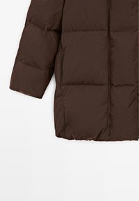 Bruine pufferjas met een boxy ontwerp, gewatteerde textuur, elastische zoom en zijzakken. Zacht, waterafstotend materiaal.