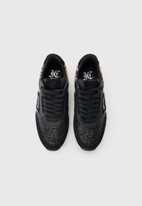 Pair of black sneakers with glitter on toes, leopard print accents on sides, black laces, and white "Just Cavalli" branding on outer edges.