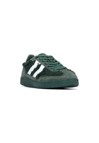 Zapatillas verdes con un empeine texturizado y suave, detalles en ante, y tres franjas blancas en el lateral. Diseño de puntera cerrada y cordones.