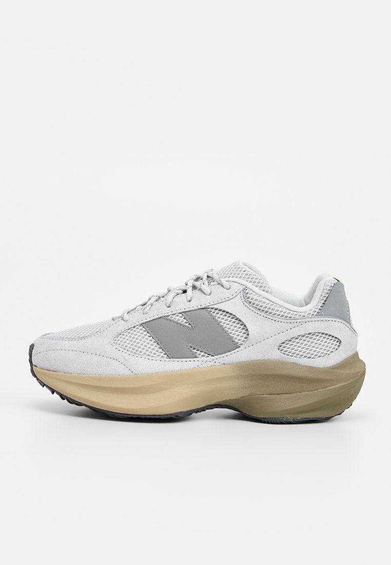 Baskets de sport grises et blanches avec une tige en maille respirante, un col rembourré et une semelle beige épaisse. Présente un logo proéminent sur le côté.
