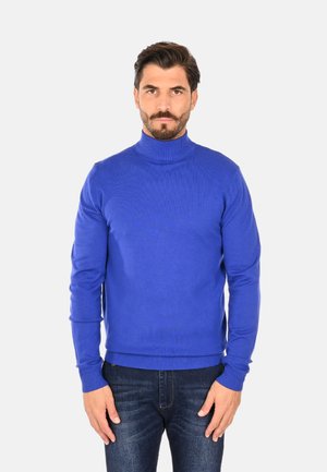 Maglione blu a collo alto realizzato in tessuto a righe, caratterizzato da un design aderente e maniche lunghe. Abbinato a jeans scuri.