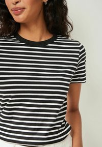 Czarna i biała koszulka w paski z okrągłym dekoltem i krótkimi rękawami, wykonana z miękkiej bawełny o dopasowanym kroju.