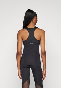 Svart rygglöst linne i slät och elastisk tyg, med en passande design och en subtil "TECHFIT"-logga på baksidan.