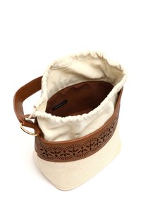 Sac seau en toile avec des bordures en simili cuir marron et un motif floral découpé au laser, équipé d'une fermeture à cordon et d'une doublure en tissu.