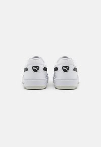 White sneakers with a smooth leather upper, black side accents, and a logo on the heel. Features a cushioned sole and streamlined design.