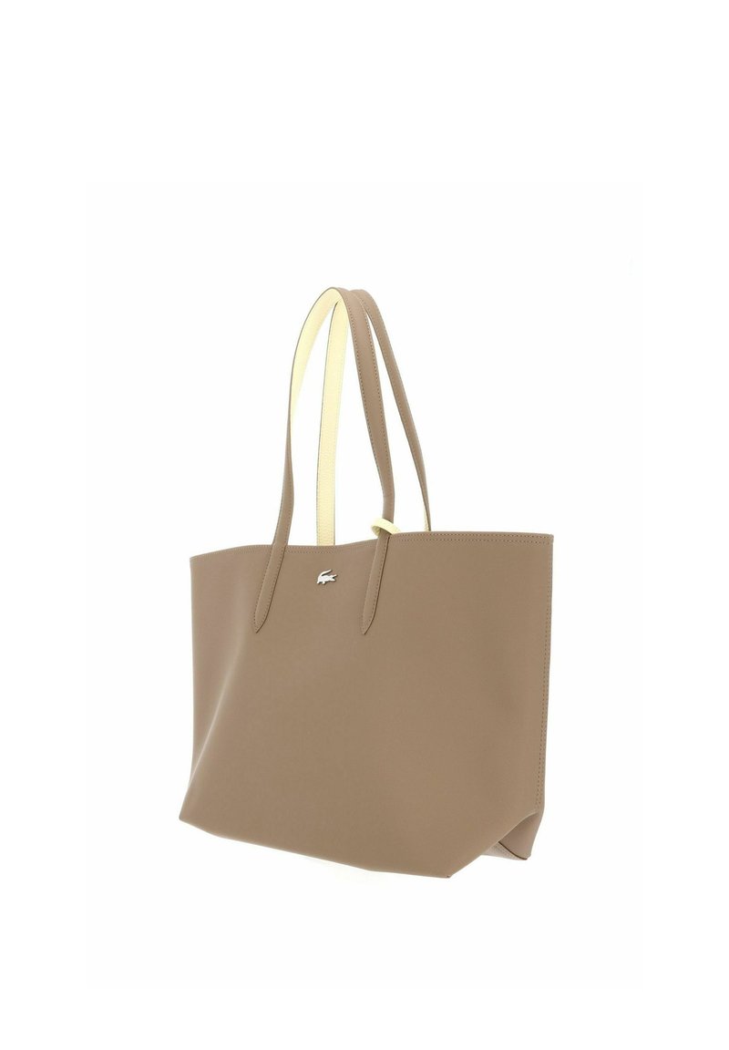 Borsa tote in pelle beige con due lunghi manici e un piccolo logo di coccodrillo in argento sul davanti al centro.