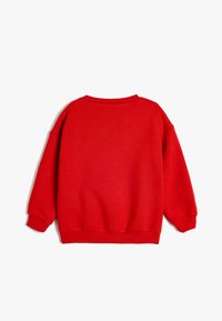 Sudadera roja con cuello redondo, hombros caídos y puños de canalé. La tela parece suave y lisa, sin patrones ni acentos visibles.