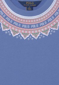 Ljusblå tröja med mönstrad rund halsringning som har rosa, vita och gröna detaljer samt upprepad "POLO"-text. Tillverkad av bomull.