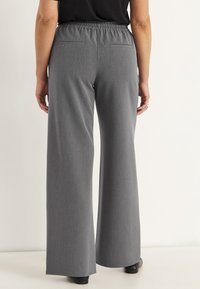 Grijze wijde broek met een gestructureerde stof, elastische tailleband en twee achterzakken, weergegeven vanuit de achterkant.