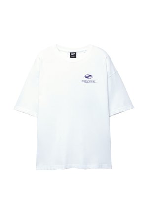 Bela bombažna majica s kratkimi rokavi, okrogel izrez in majhna vijolična oznaka spredaj. Ima sproščen, kvadraten kroj.