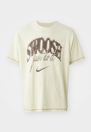 Lys gul bomulds T-shirt med en afslappet pasform, der har brun grafisk tekst "SWOOSH" og "just do it" sammen med et Nike swoosh-logo.